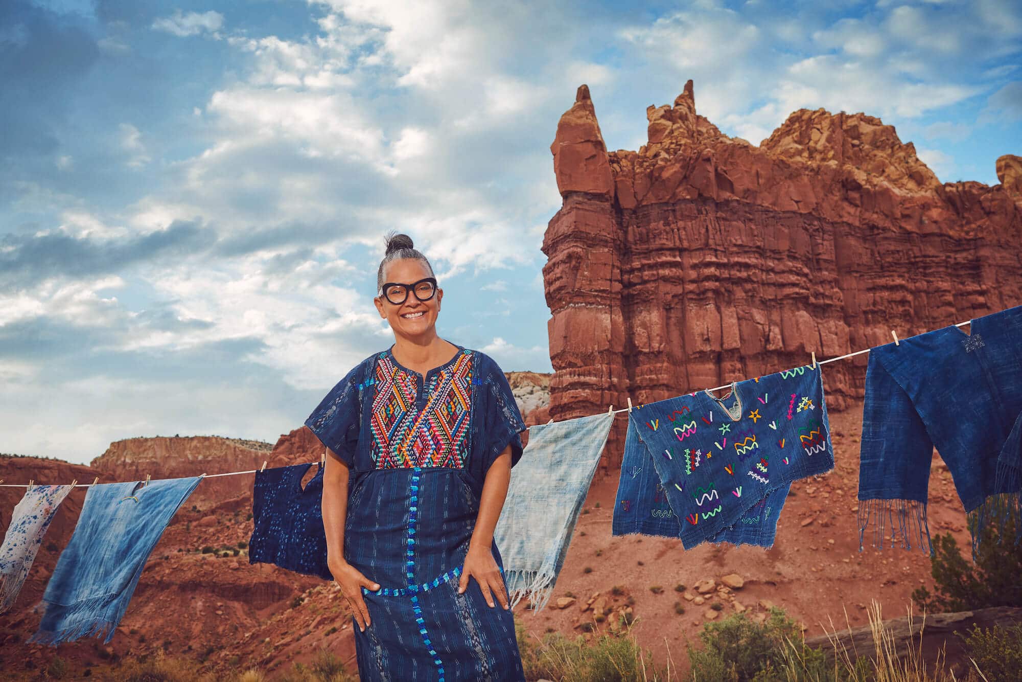 Amy Yeung, 4Kinship founder, standing with some of her garments against a striking background of the New Mexico mountains