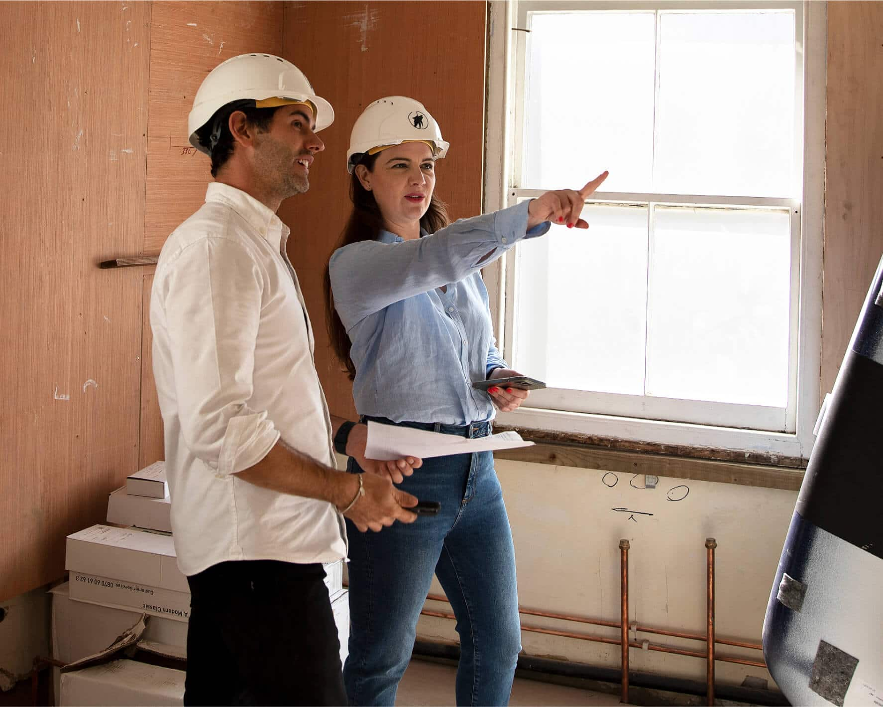 Two people with hard hats discuss a construction project they’re working on.