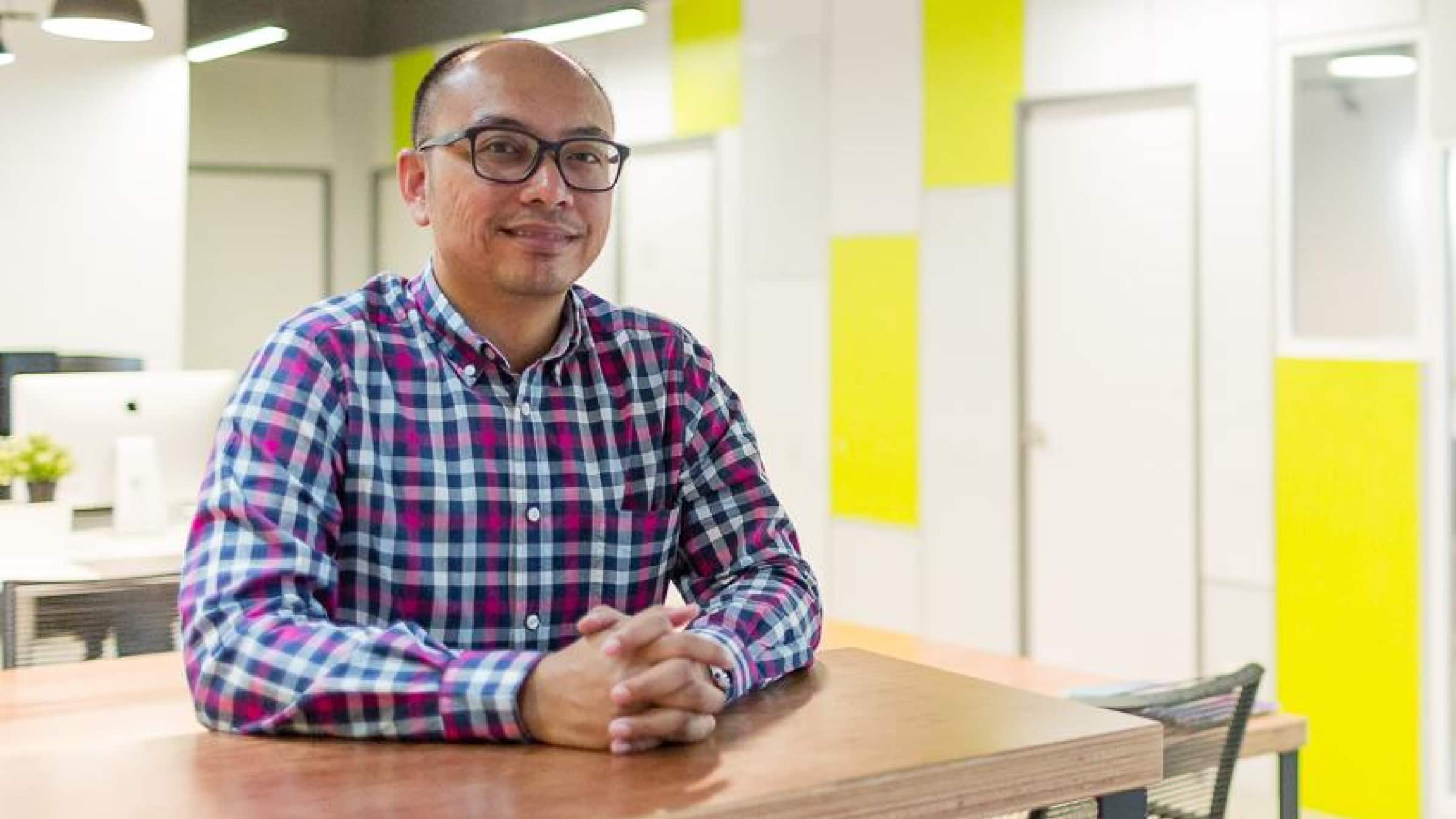 Aiman Ezanee from Extracc sitting at a table in the company offices.