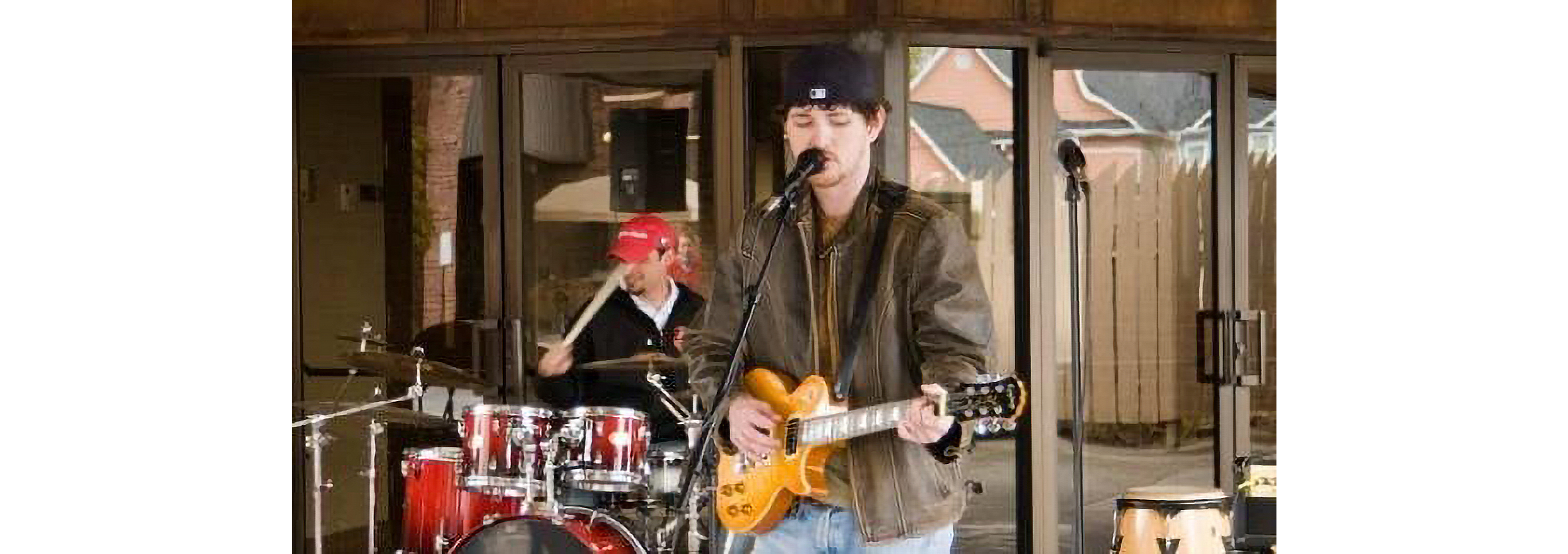 Tate Henshaw playing guitar on stage, with a drummer behind him.