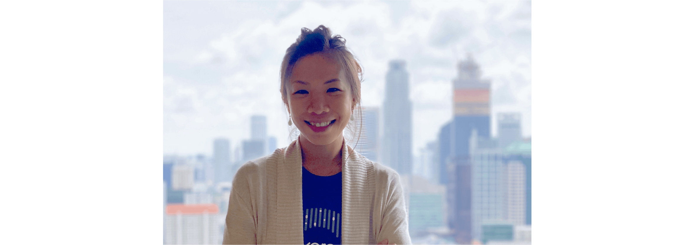 Leriz Fan stands in front of a highrise landscape, smiling at the camera.