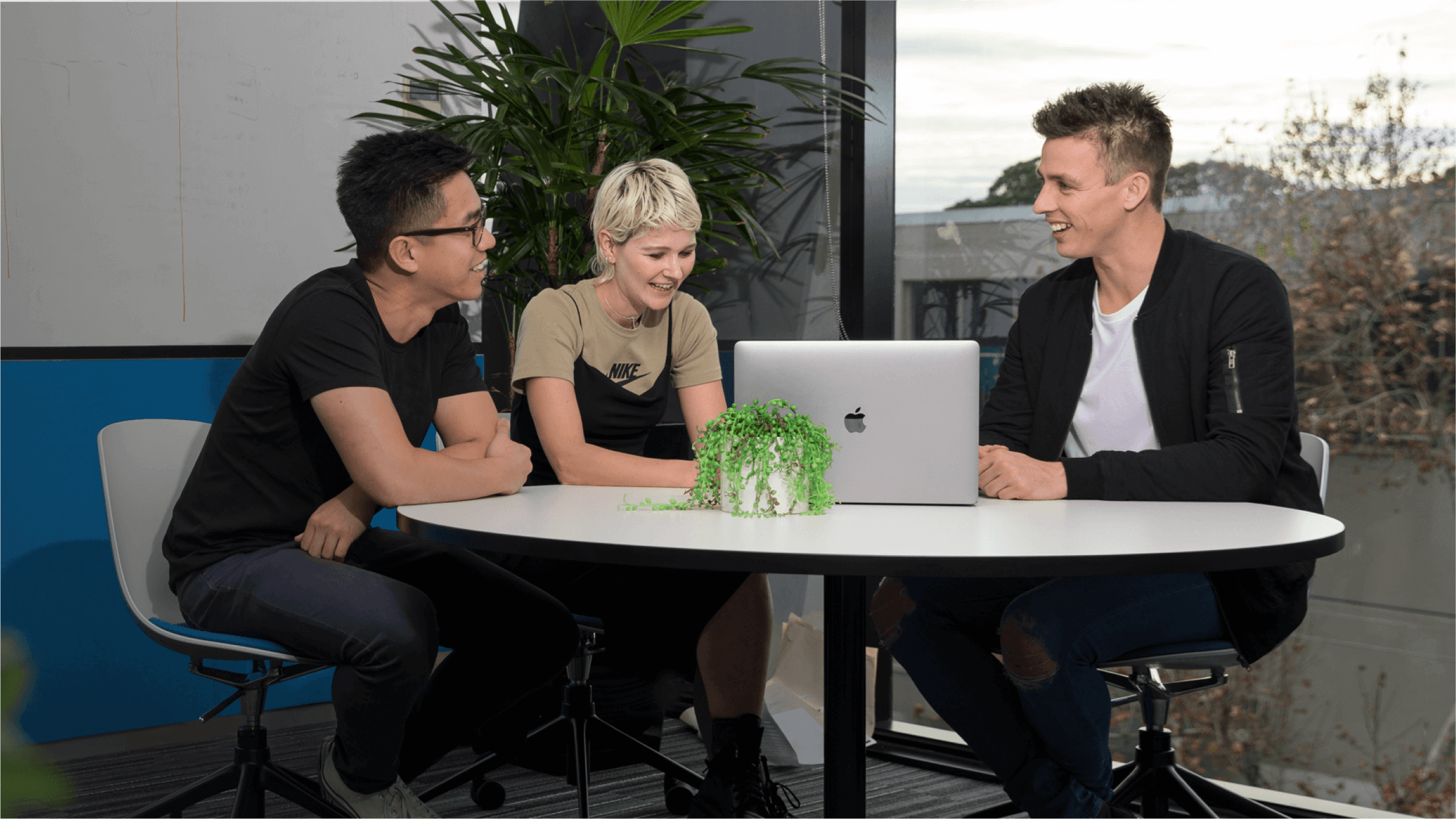 Two small business owners sit at a table discussing accounts with their advisor while using Xero on a laptop.