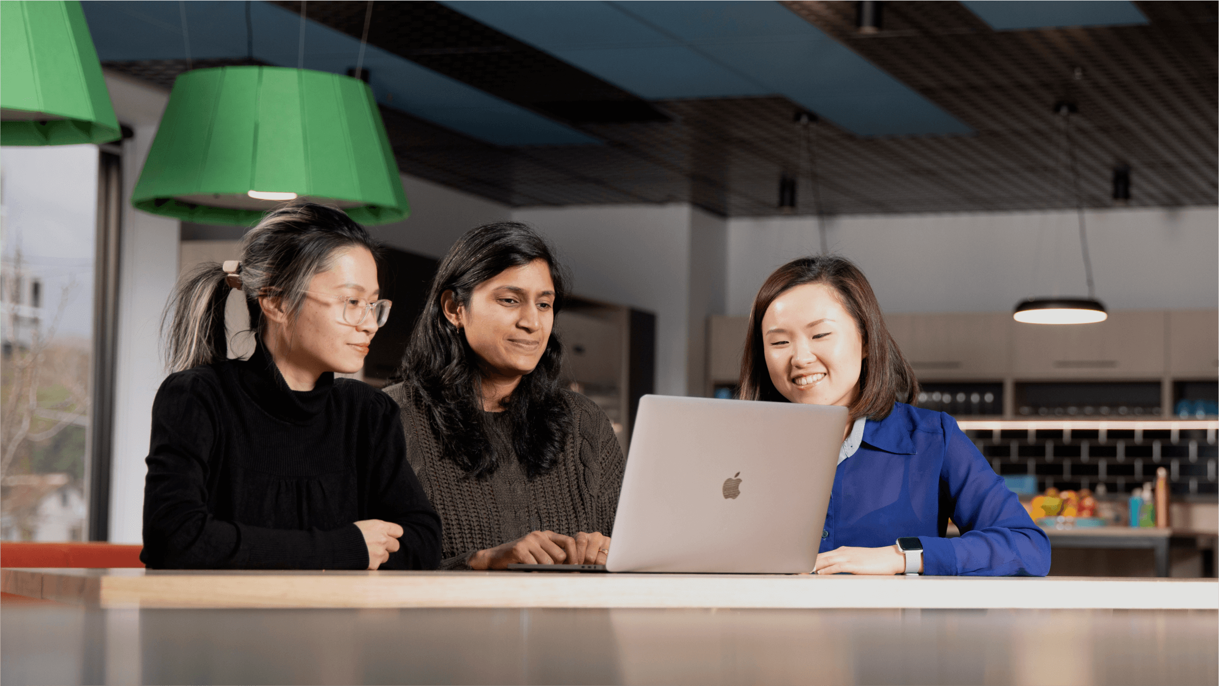 Three students share a laptop as they work through a business studies exercise online.