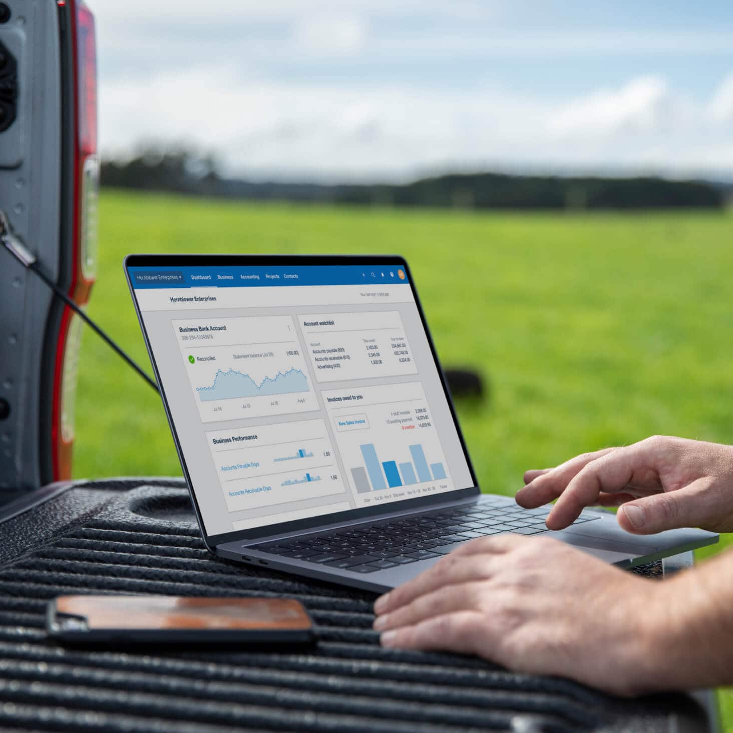A farmer uses the main Xero dashboard on their laptop, from out in the field, to keep track of their agriculture accounting.