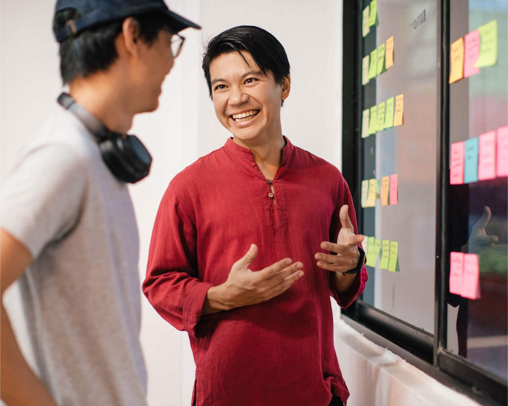 A startup founder and a team member discuss how to prioritize tasks that are listed on colour-coded sticky notes. 