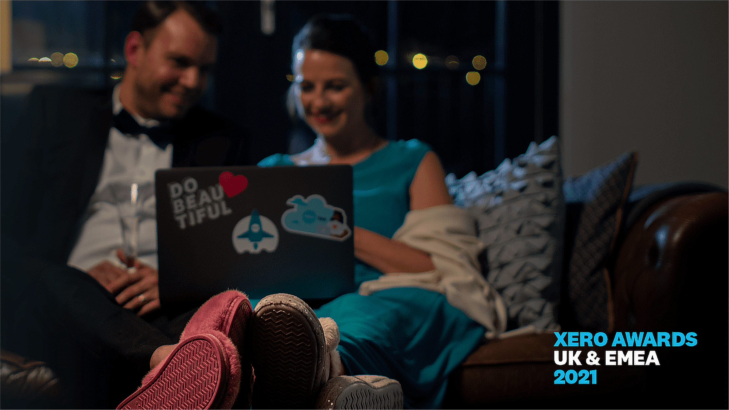 A man and woman in evening dress watch the Xero Awards online from the comfort of their sofa.