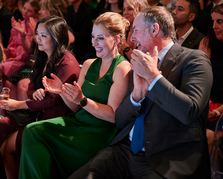 Two smiling Xero Awards guests clap during the ceremony