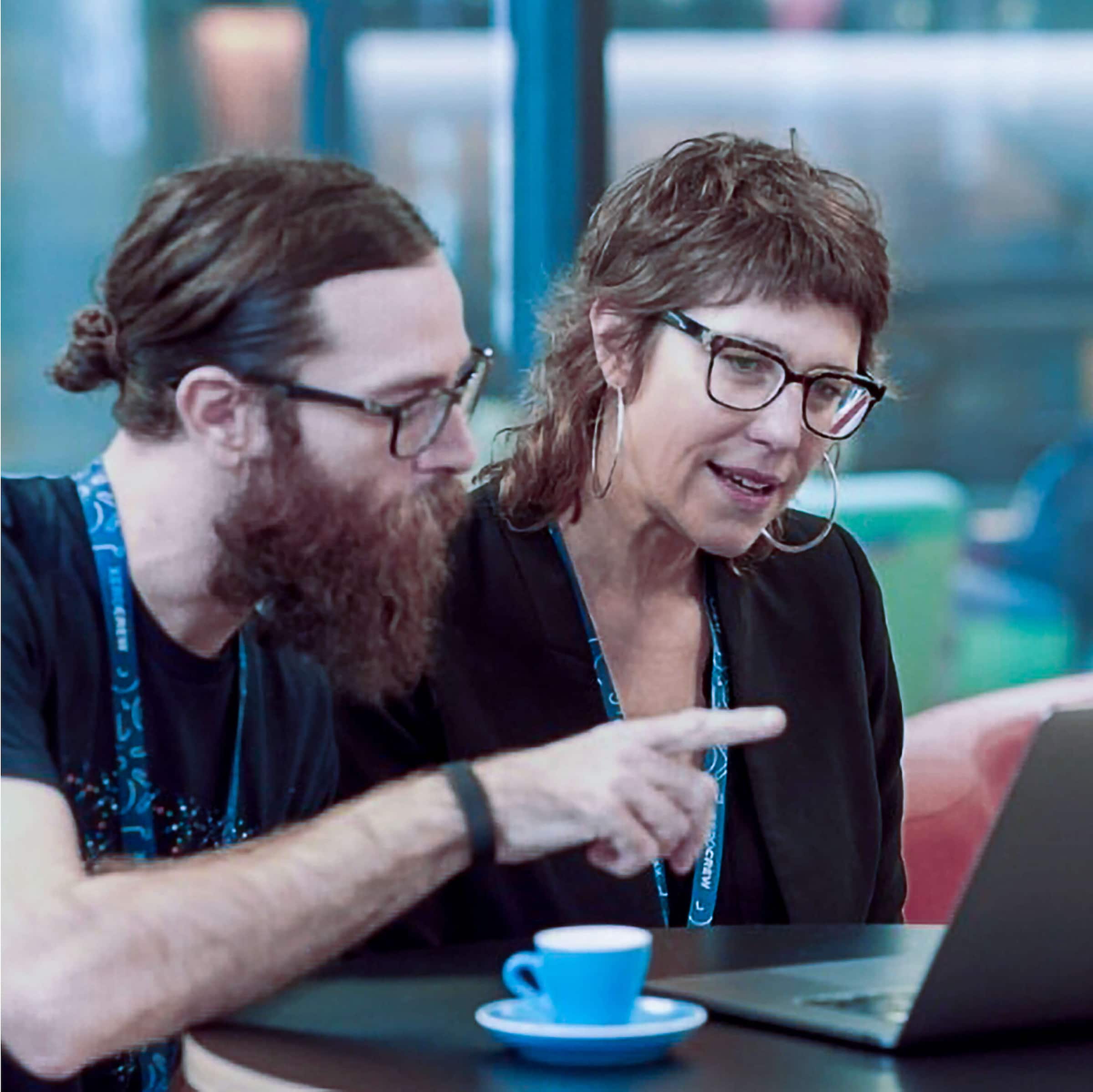 Two designers look at a laptop screen while discussing design ideas.
