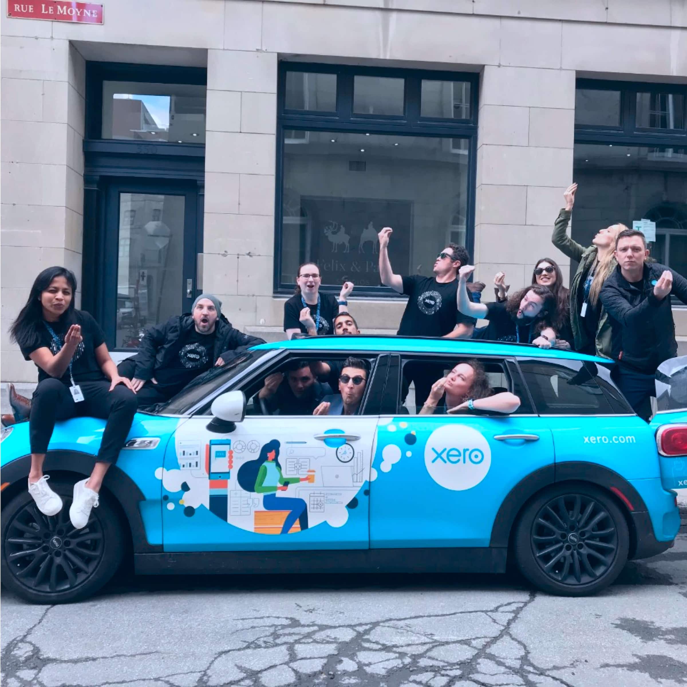 The Xero Wellington team and the Xero Canada team take a wacky pose in front of a Xero-branded car.