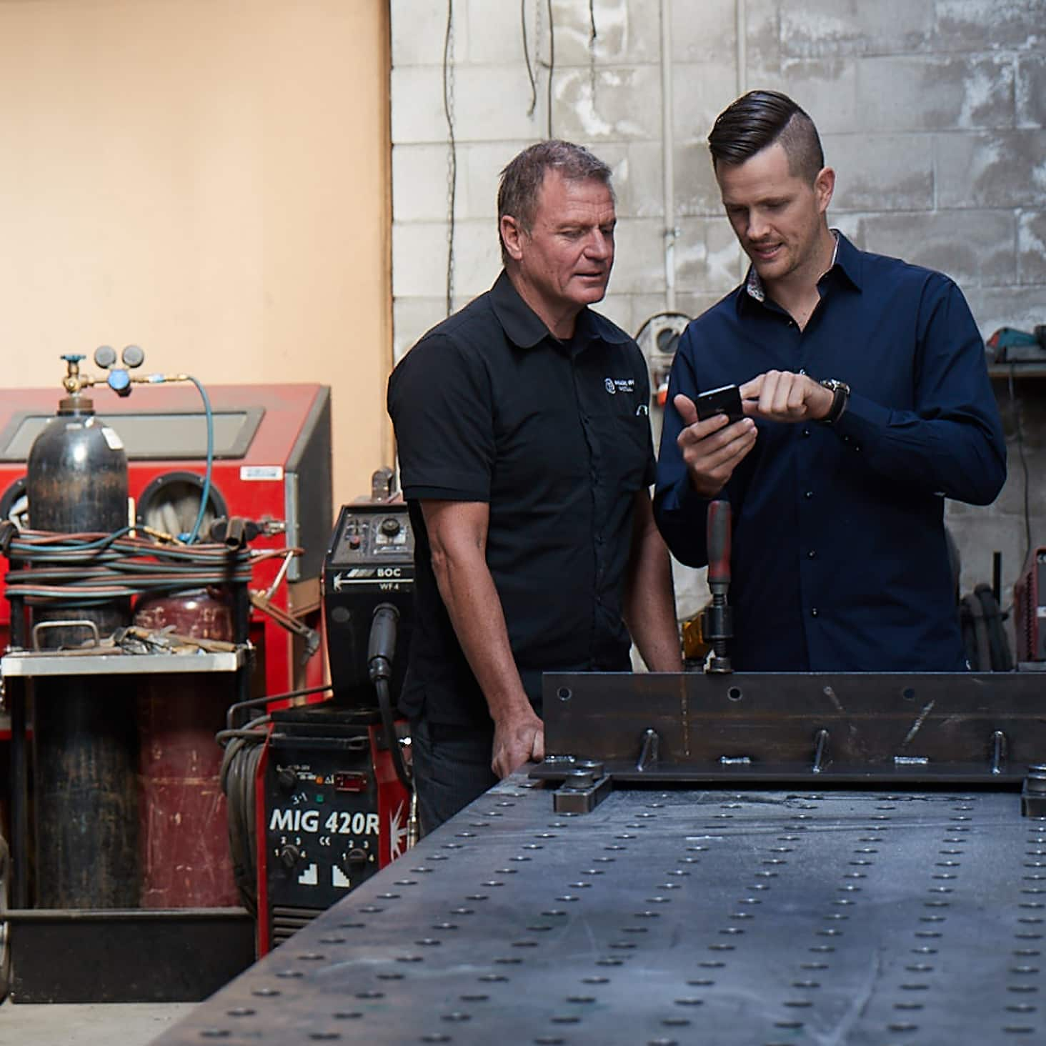 A small business owner shows their employee how to view payslips on the Xero Me mobile app.