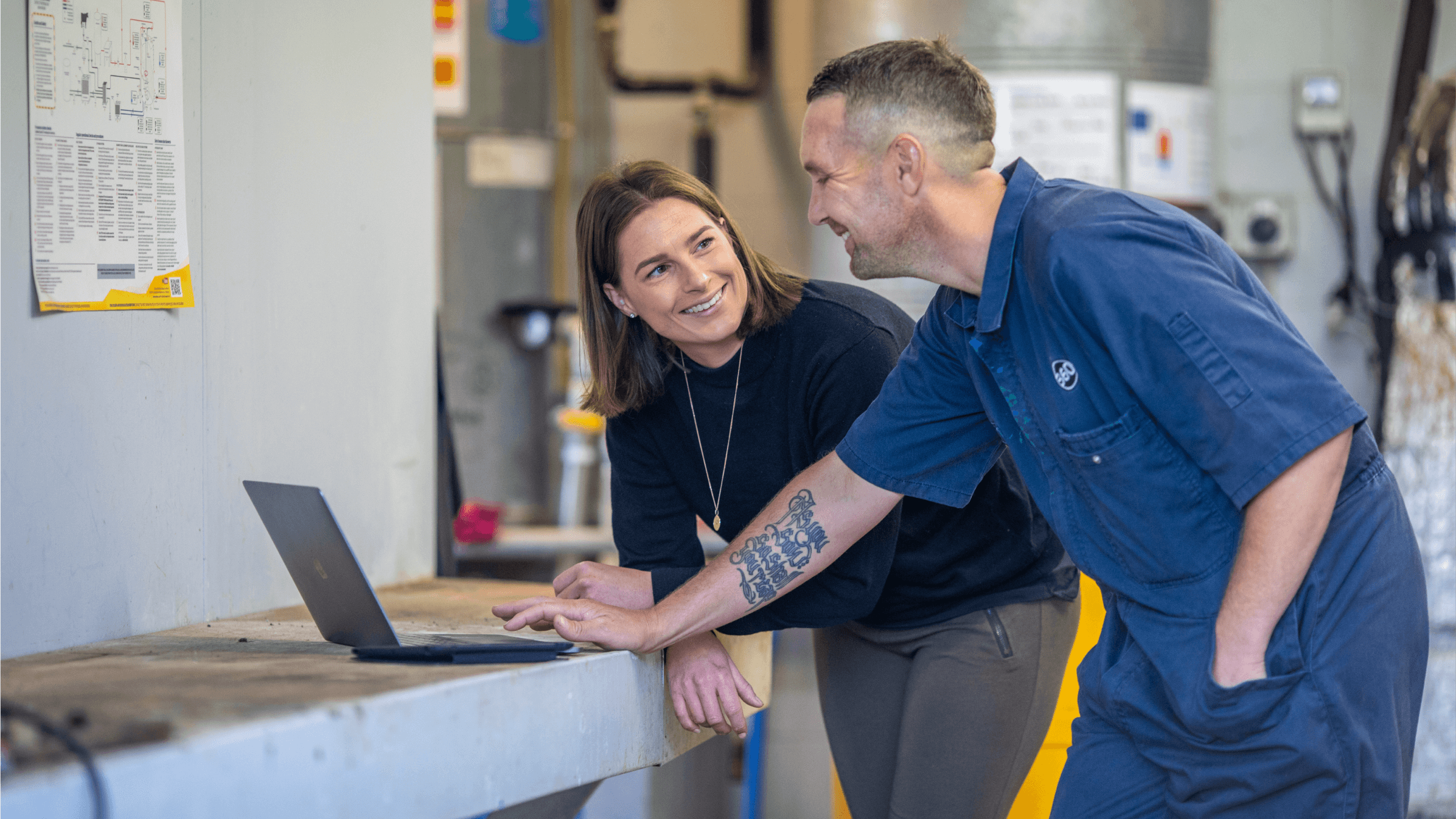 A tradesperson shares a light-hearted moment with a colleague while invoicing for the job they’ve just finished