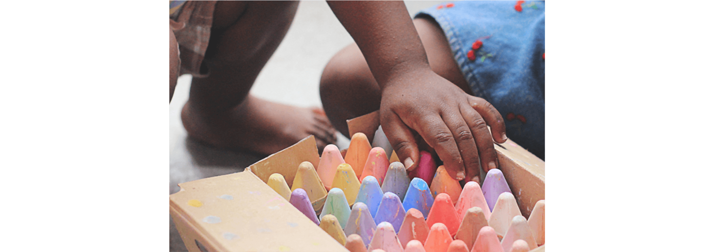 A child opens a large carton of different coloured chalk that’s been donated to their school.