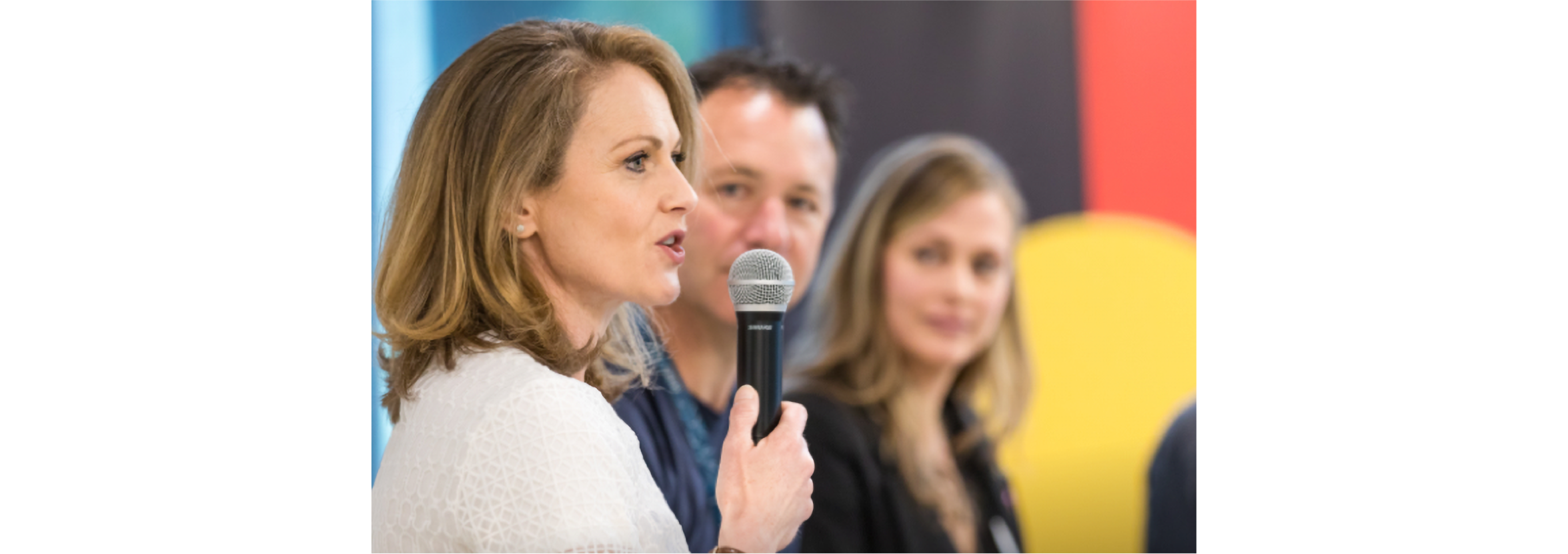 A woman speaking at an event, holding a microphone.