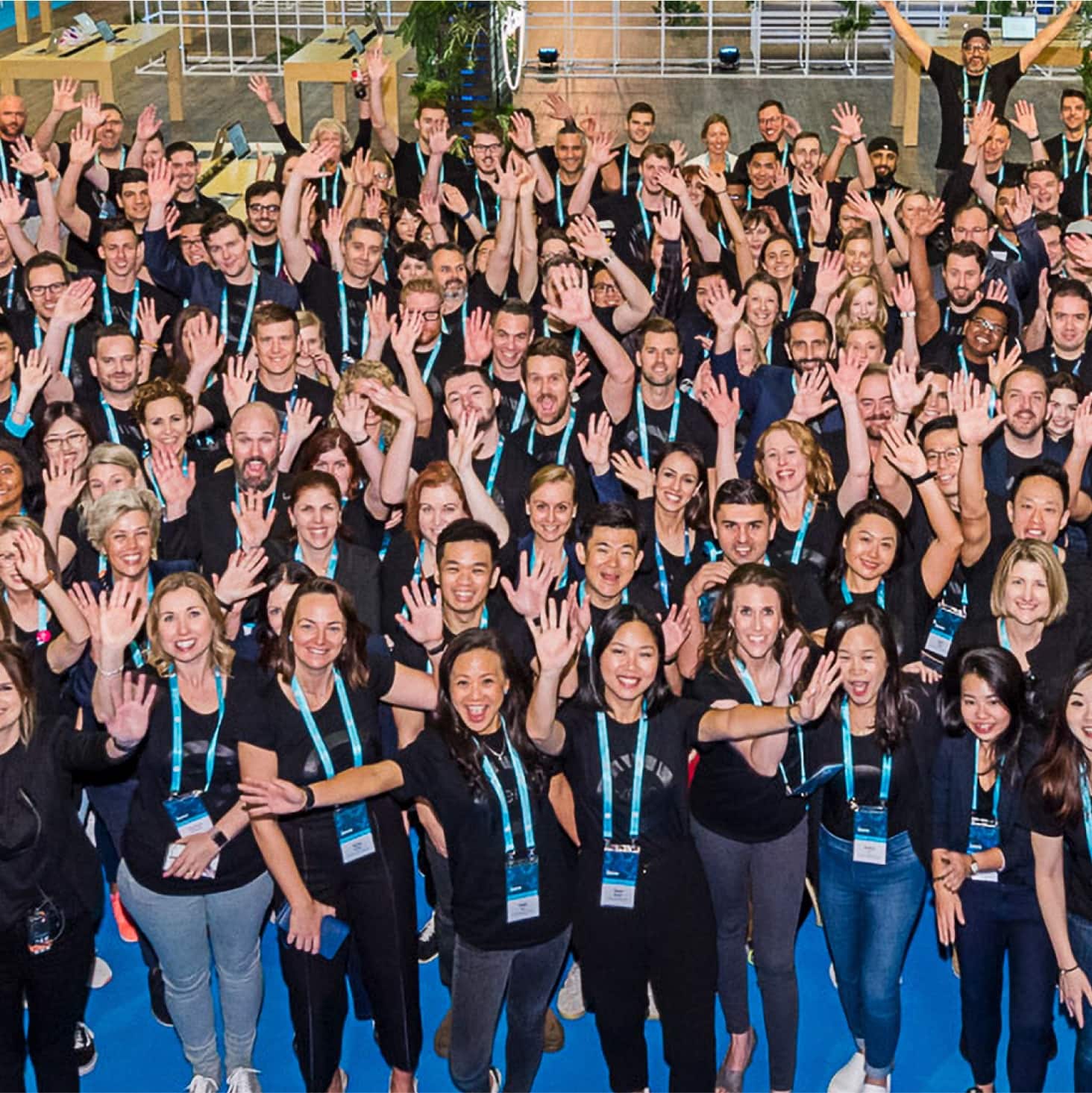 A large room full of Xero staff raising their arms in the air.