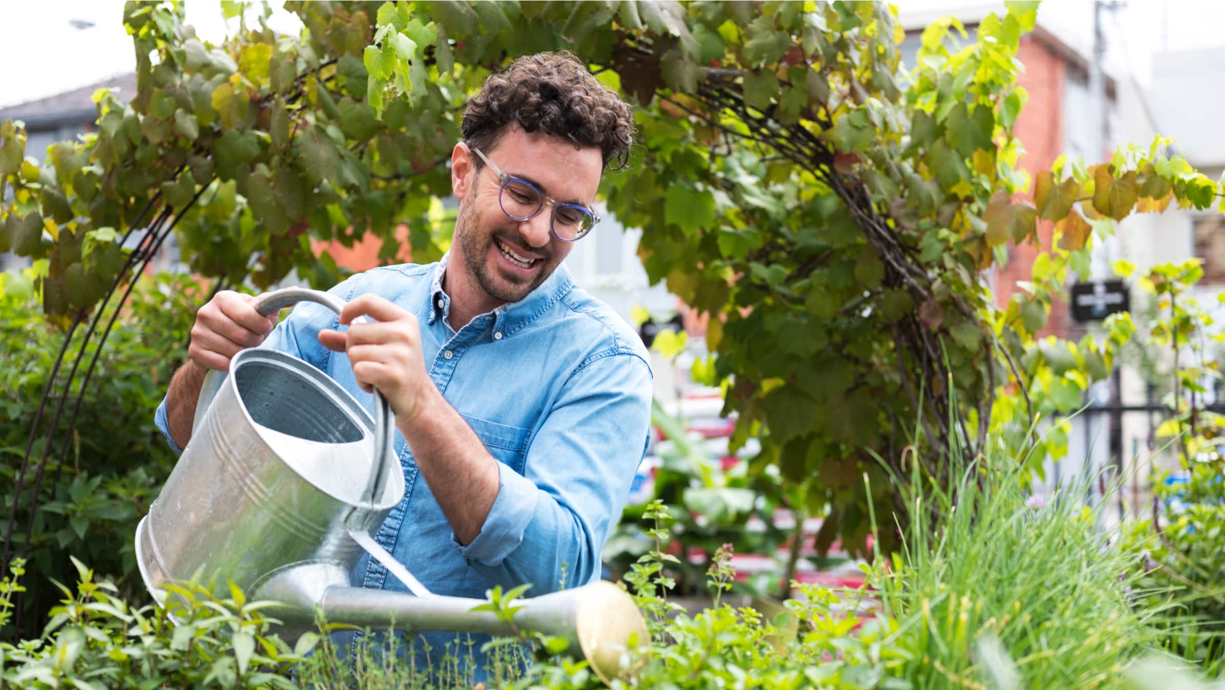 A person holding a watering can, adding water to their plants.