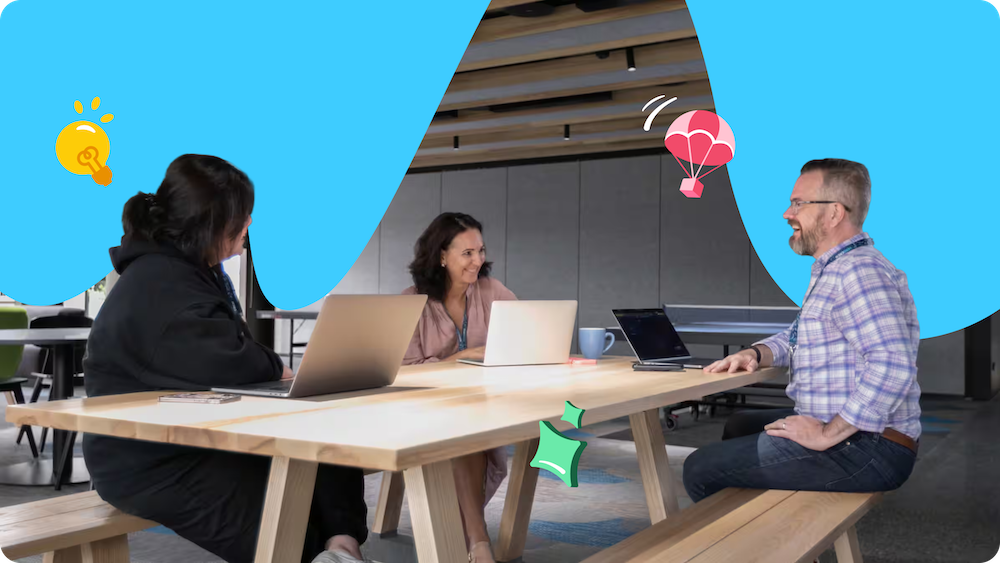 Three Xero employees share a laugh while meeting in an informal work space, laptops open in front of them.