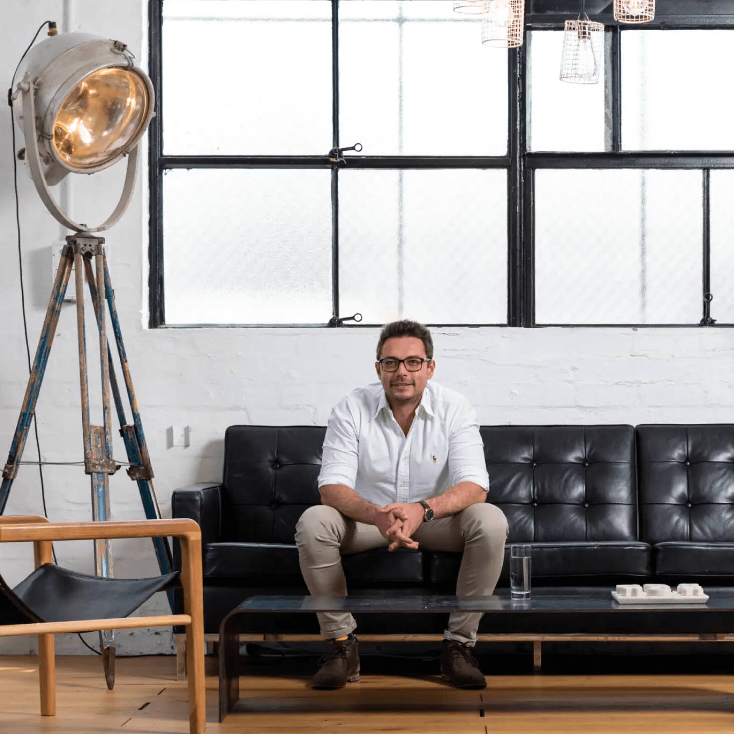 A Xero partner sitting on a black couch under a window.