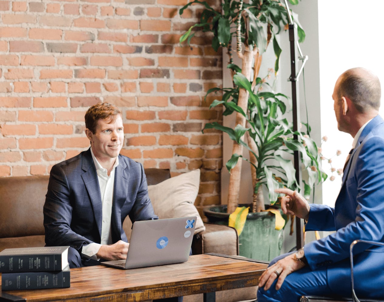Two men in suits talking over a laptop