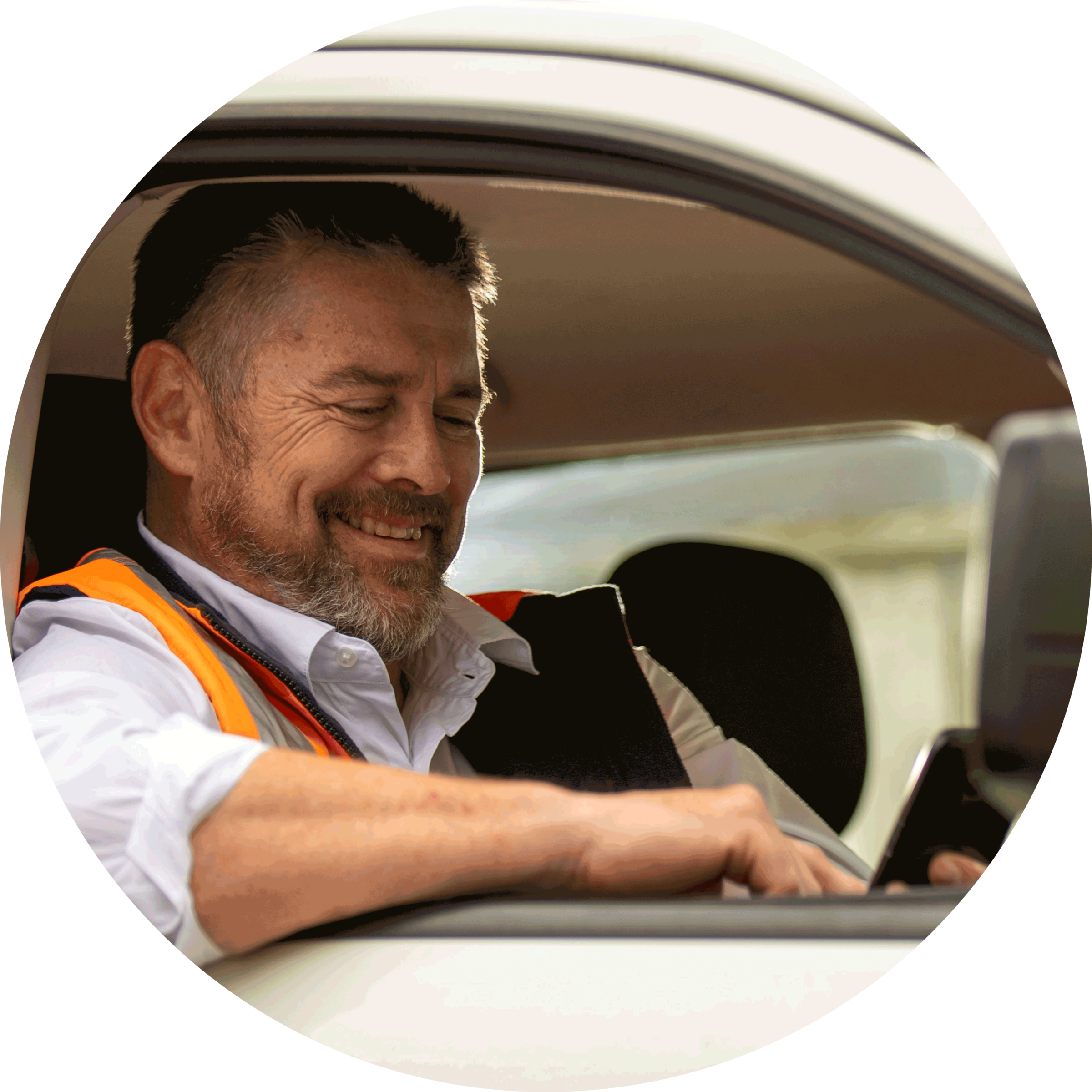 Tradie smiling at phone in parked car.