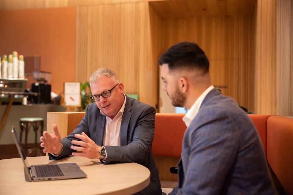 An advisor meets with his client. They analyse what’s on the computer screen in front of them.