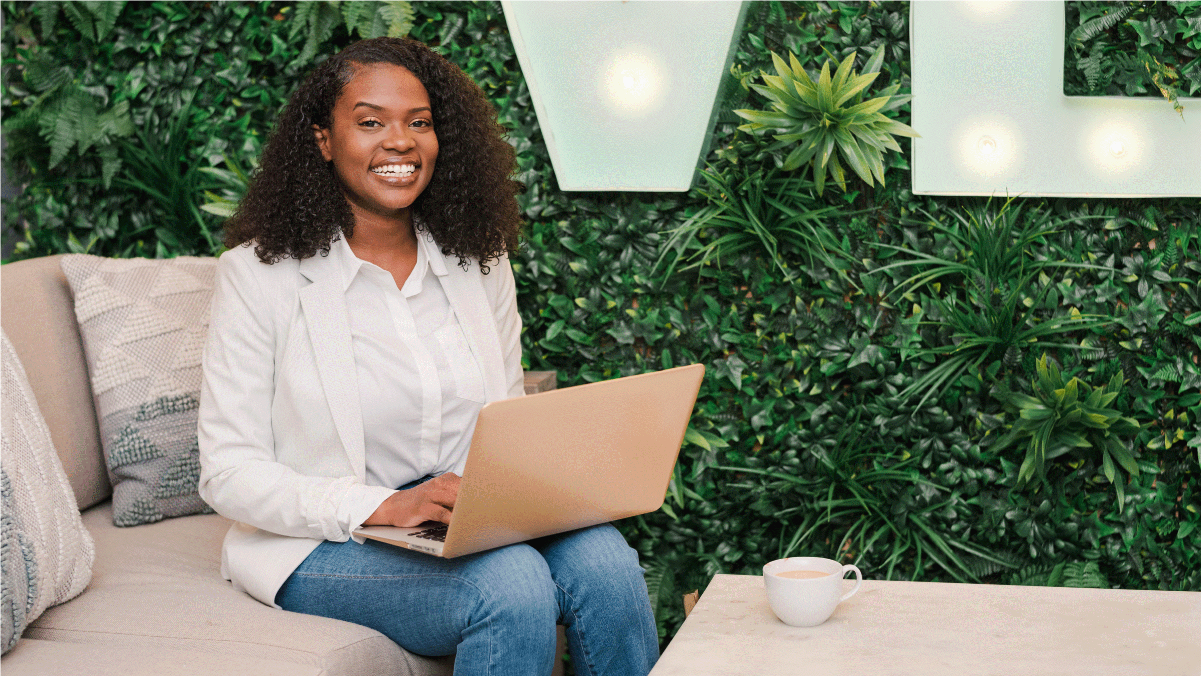 An accountant sits in an office lounge, working on her accounts with a laptop on her knees.