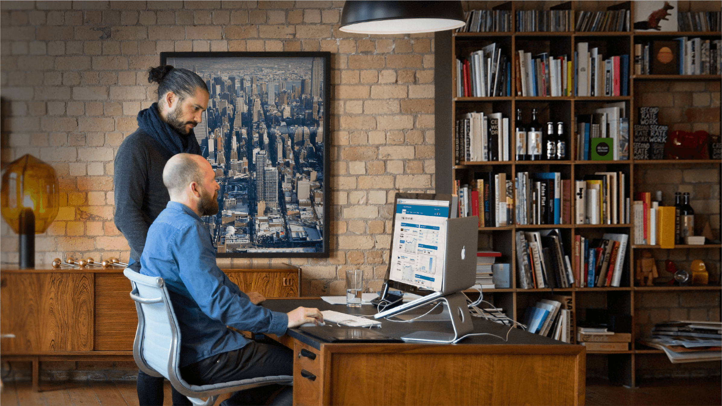 Two small business owners at an office desk look through their Xero accounts.
