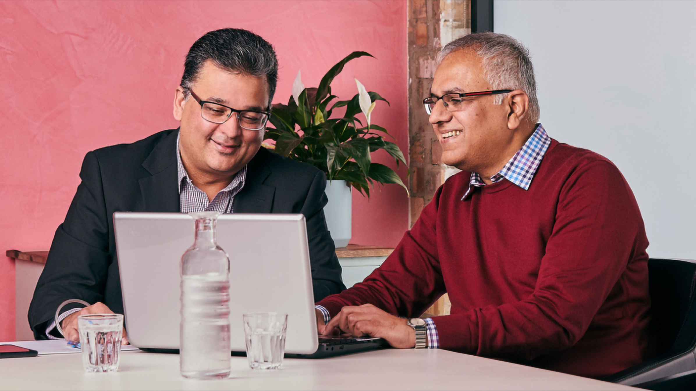 An accountant and their client sit in front of a laptop using cloud-based software to run through business information.