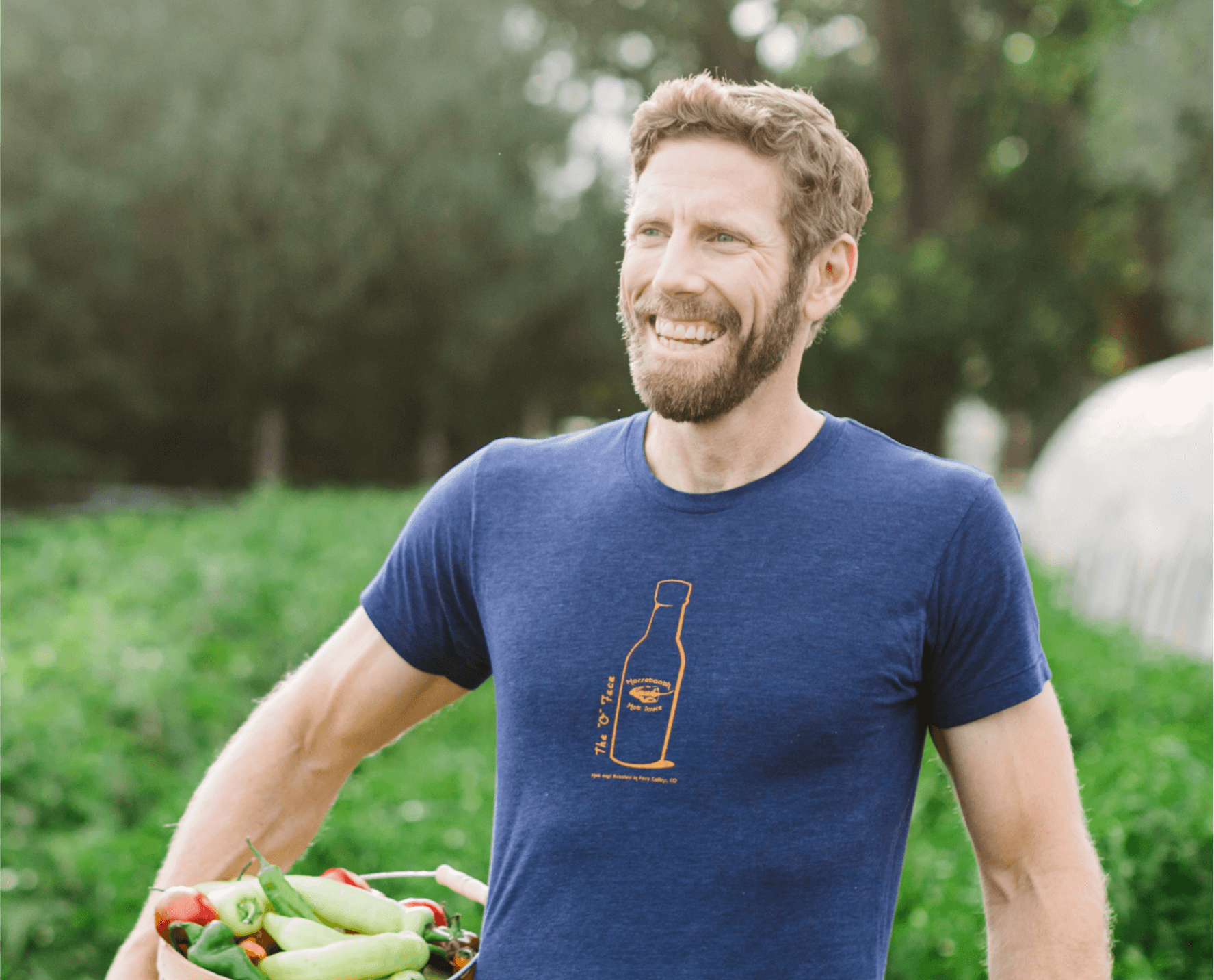 John Comeau from Horsetooth Hot Sauce smiles, holding a box of vegetables.