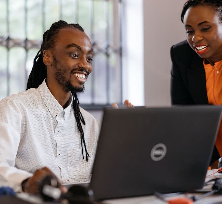 Two people talking over a laptop.