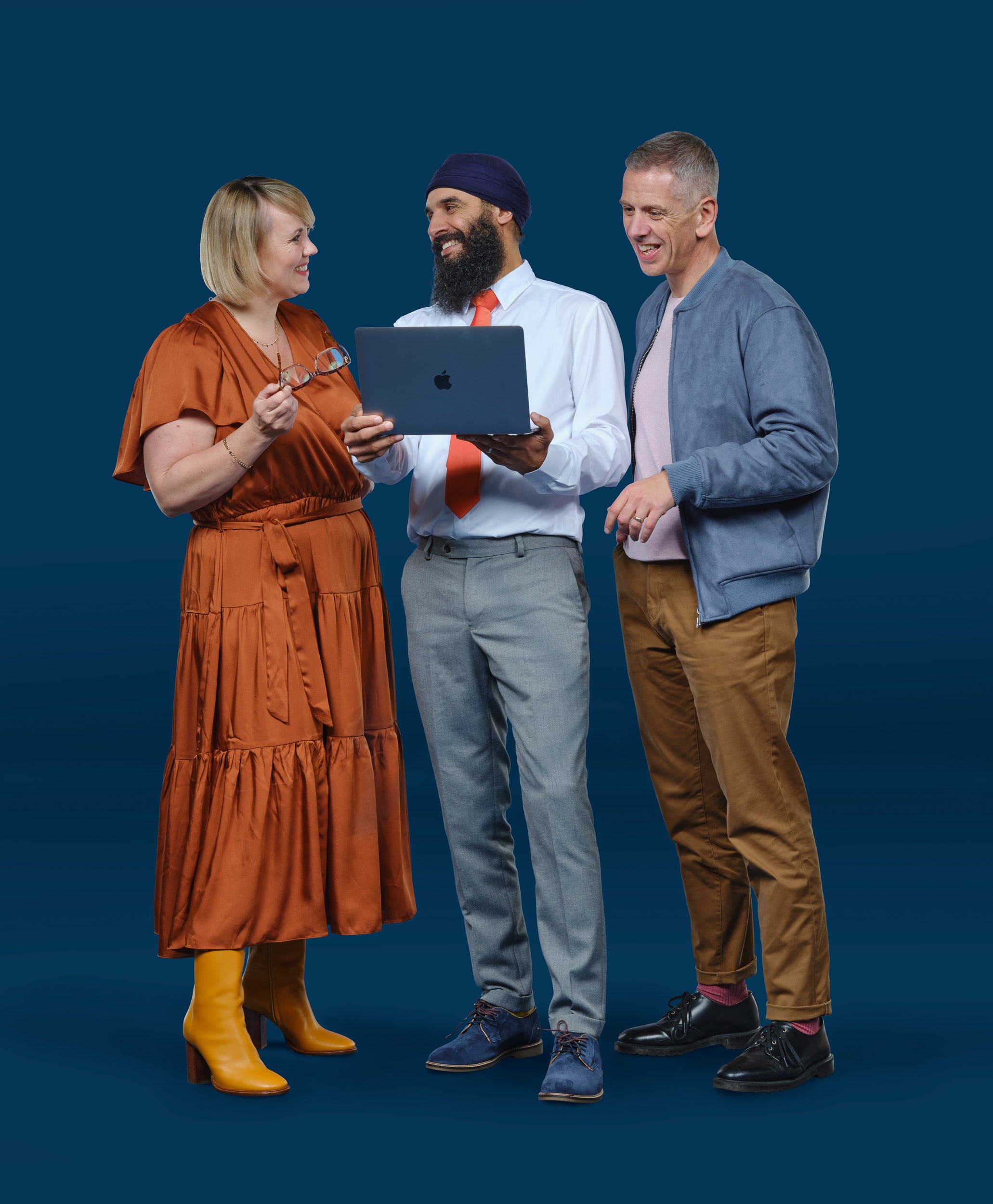 Three accountants looking at a laptop and each other and smiling