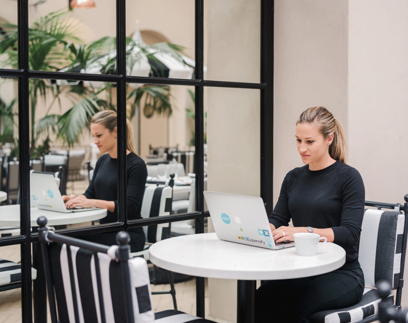 Person typing on laptop in a cafe.