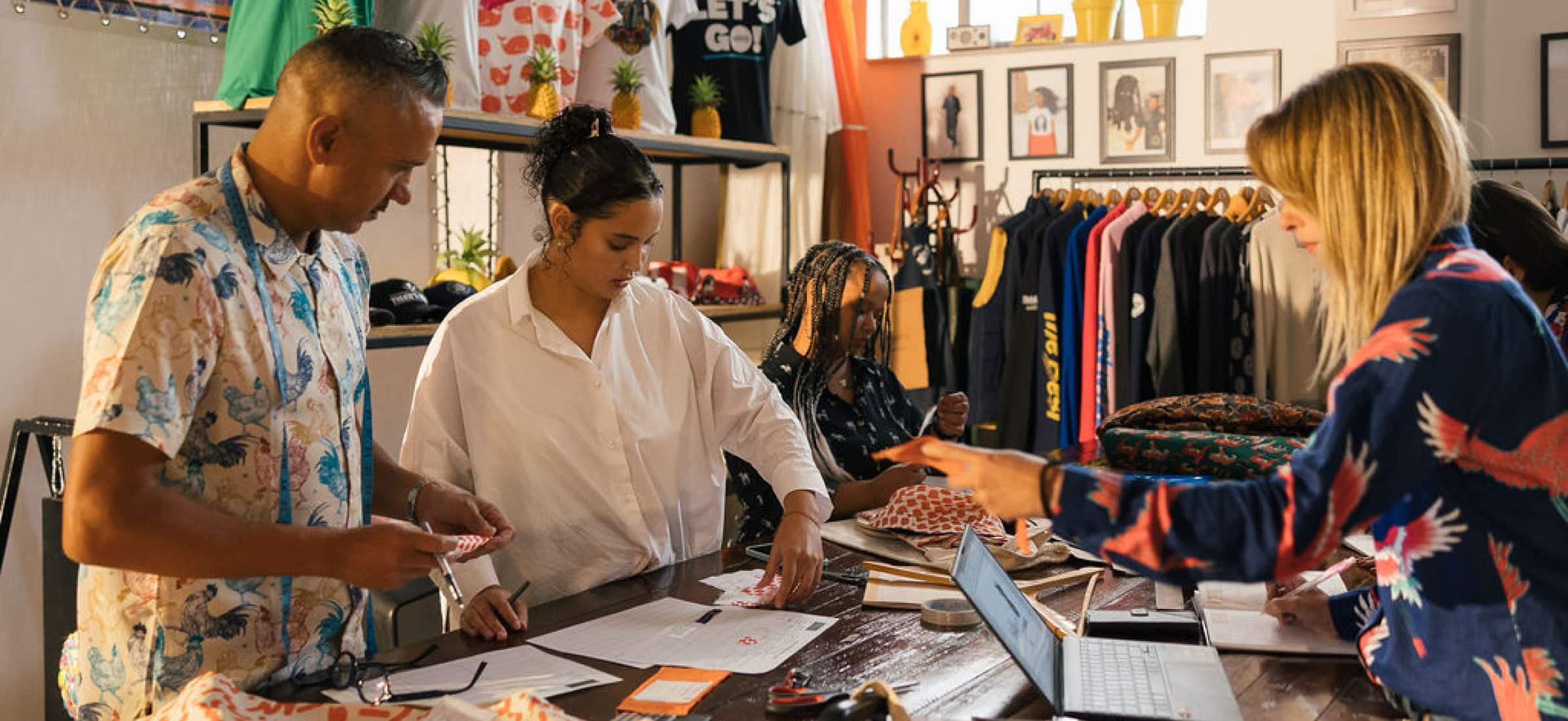 Adrian working with colleagues surrounded by fabrics