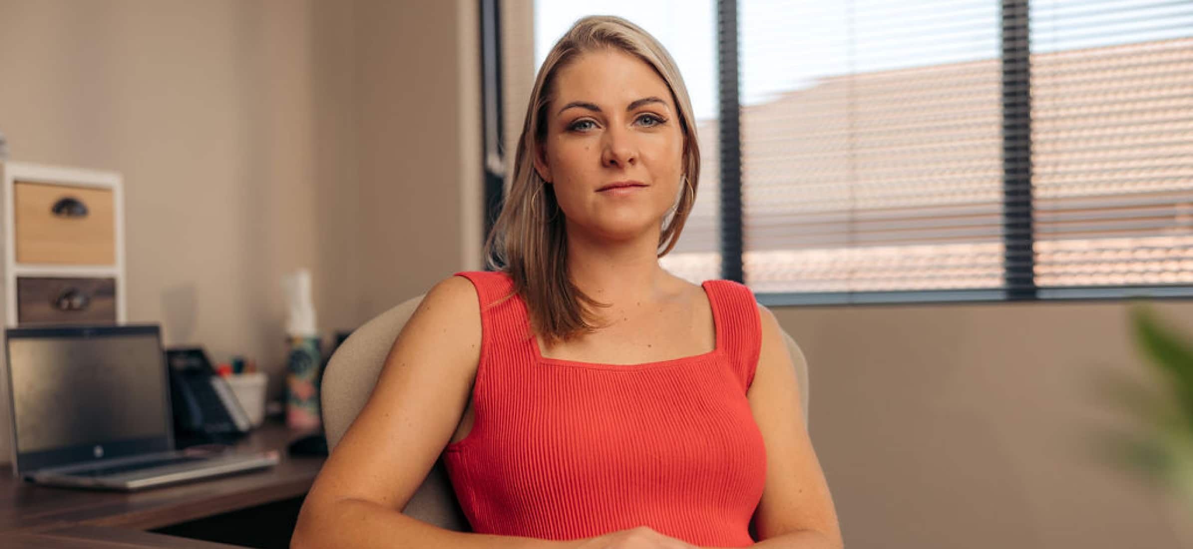 Mariaan Leonard sitting at their desk looking at the camera.