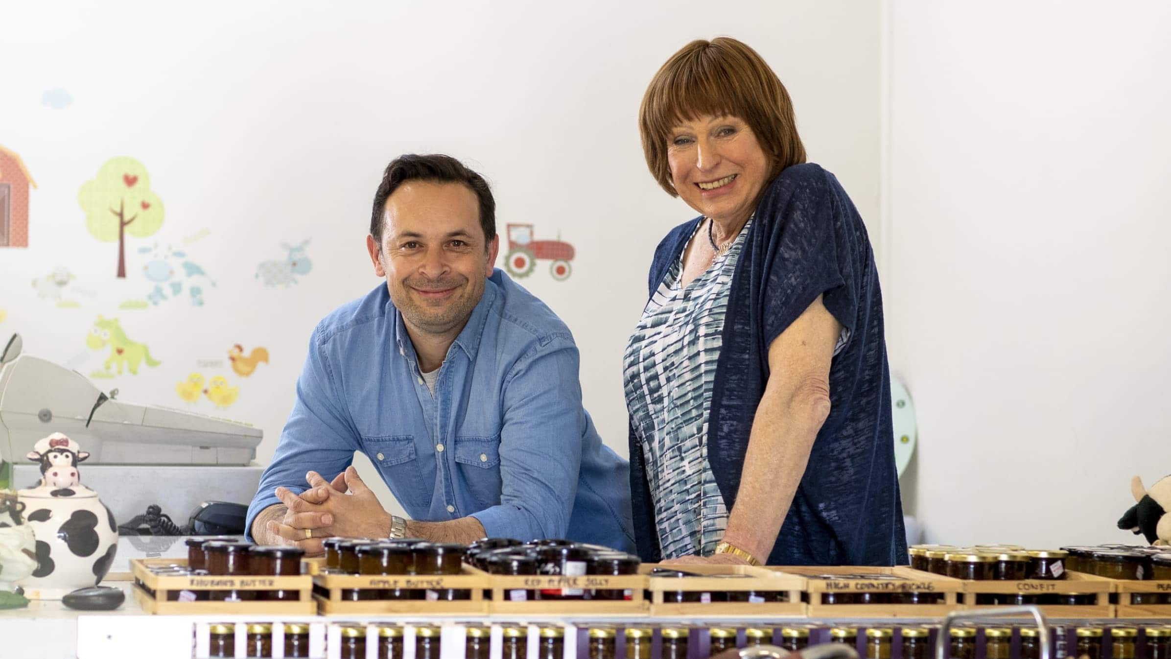 Pablo and Colleen Dennison relax for a moment. Jars of confit and fruit butter stand in small wooden crates ready for sale.