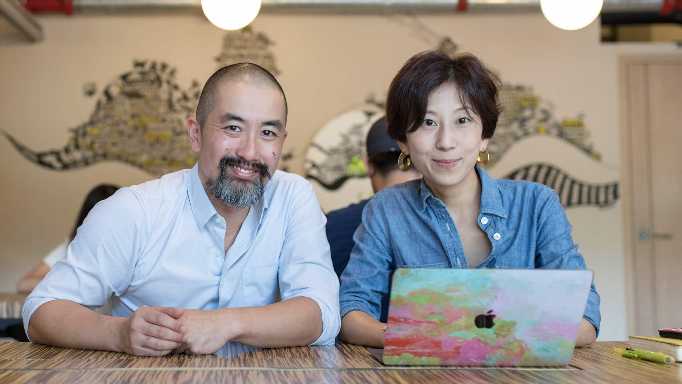 Elaine Tsung, founder and CEO of Garage Society, sits at a high office table with her computer next to a colleague.