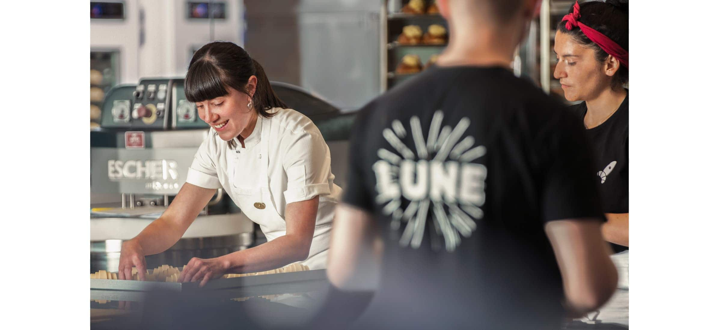 Kate preparing croissants and laughing in the kitchen with her staff.