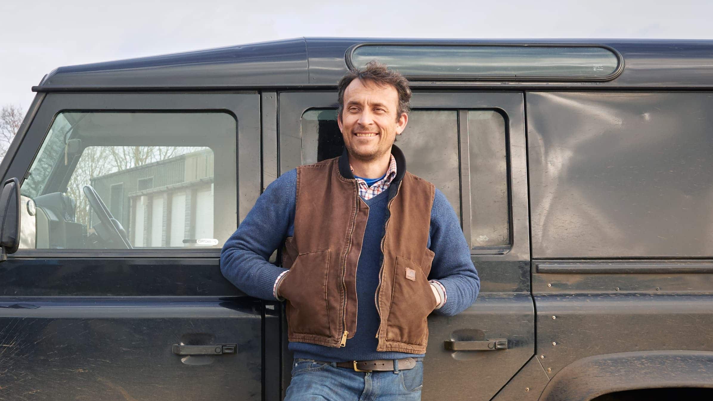 Richard Fishenden, founder of blacksmith business Made by the Forge, stands in front of a Land Rover truck.