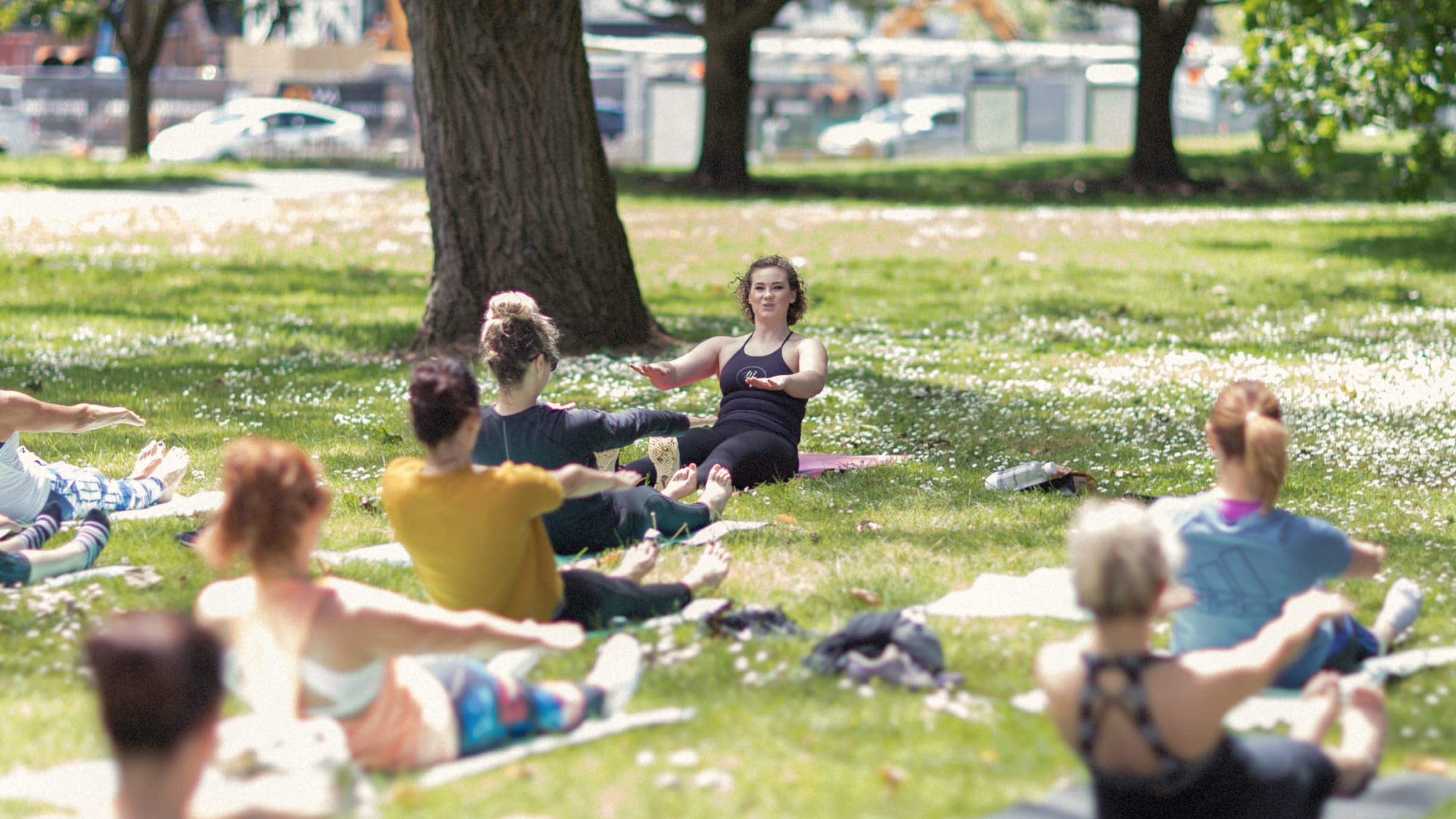 Phoebe Heyhoe from MatWorks Pilates leading a pilates class in a park.