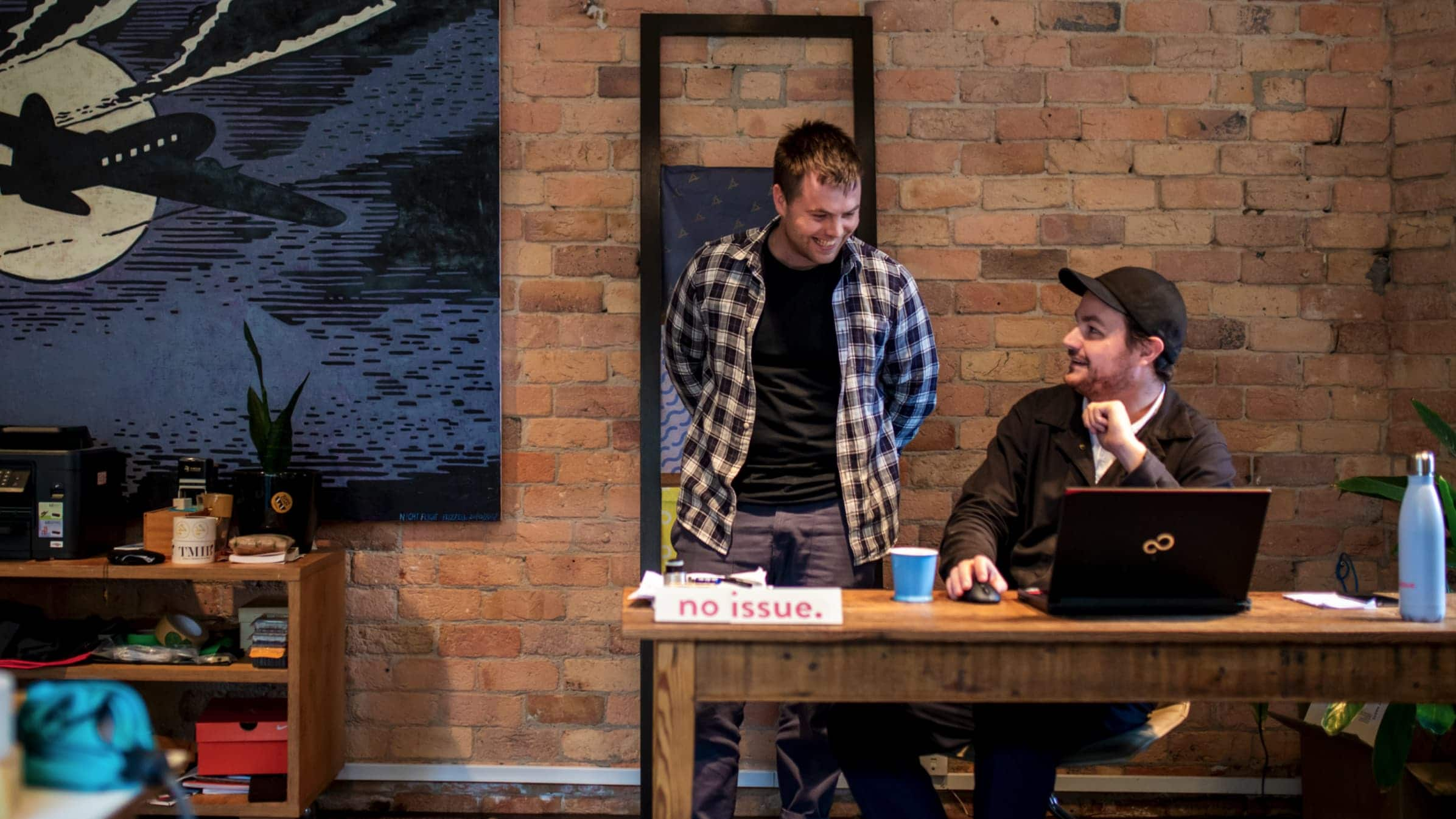 Josh Bowden and Augie Gruar chat infront of an open laptop in their office. 