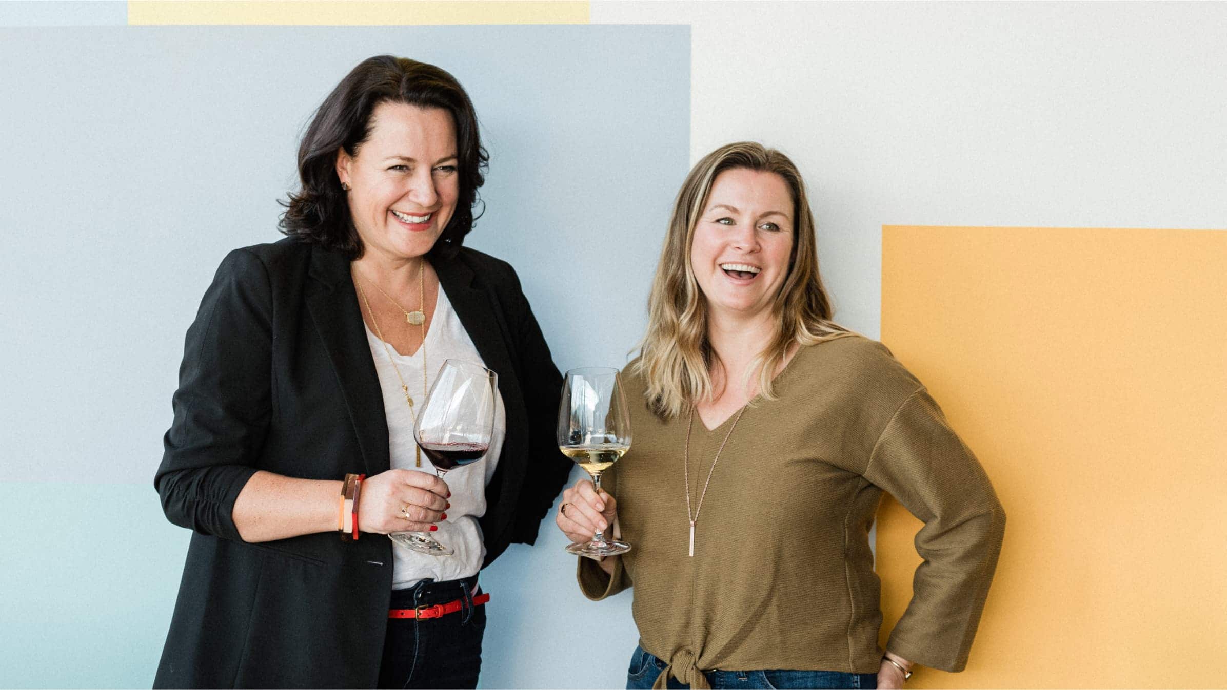 Nicole Hughes and Anne Siegel, owners of Olive and Poppy, laughing over a glass of wine.