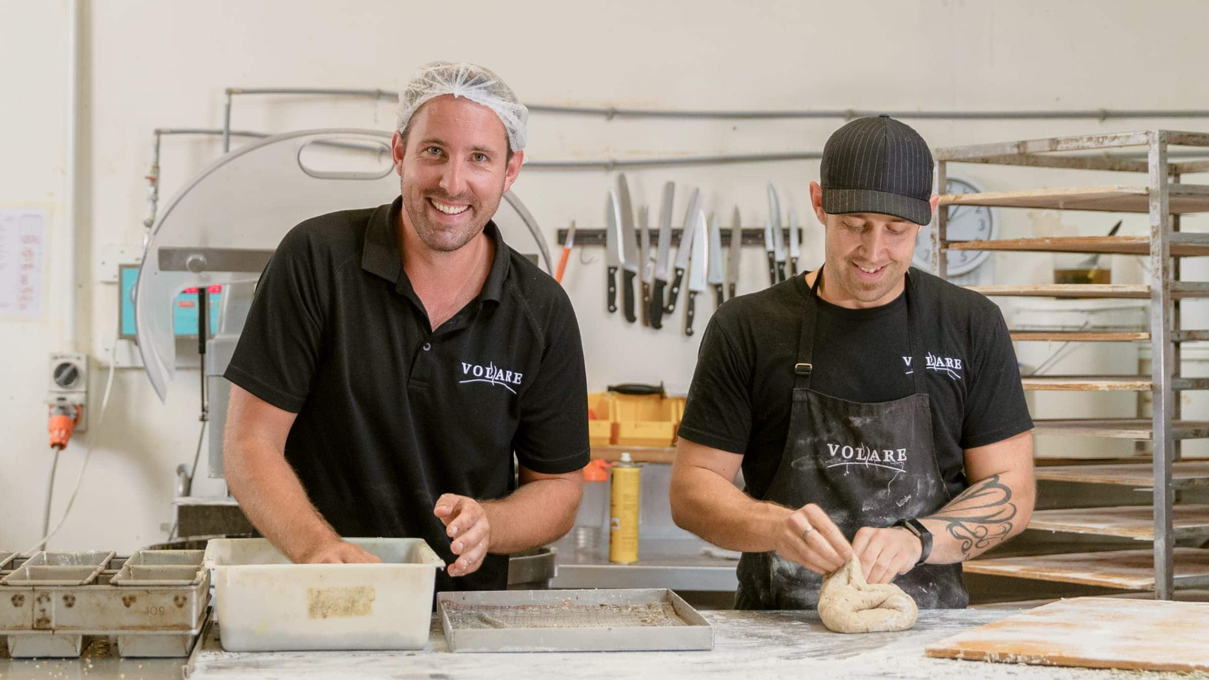 Two bakers prepare dough in a commercial bakery.