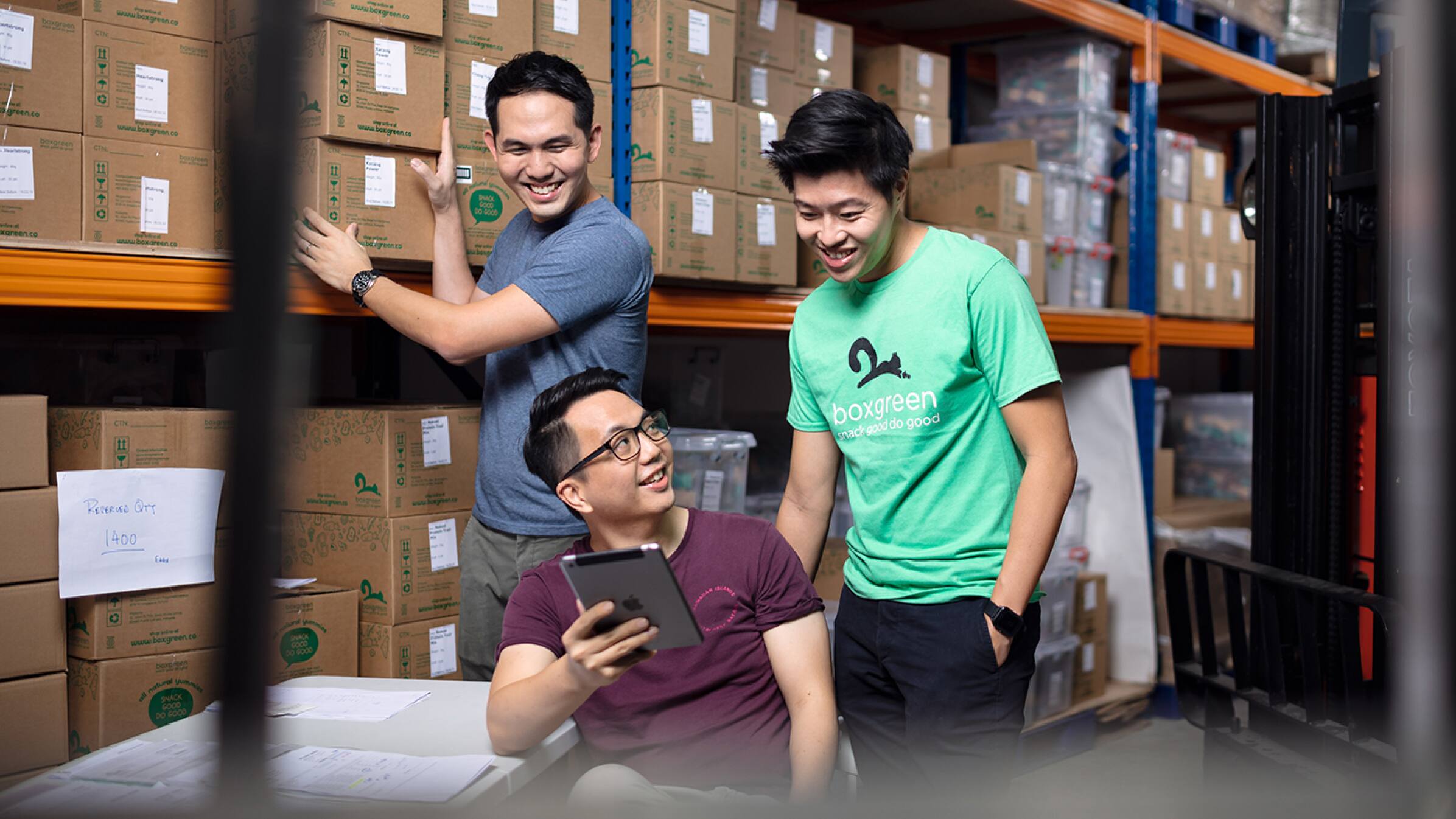 Andrew Lim and Walter Oh, founders of Boxgreen, standing in their storage warehouse with a colleague. 