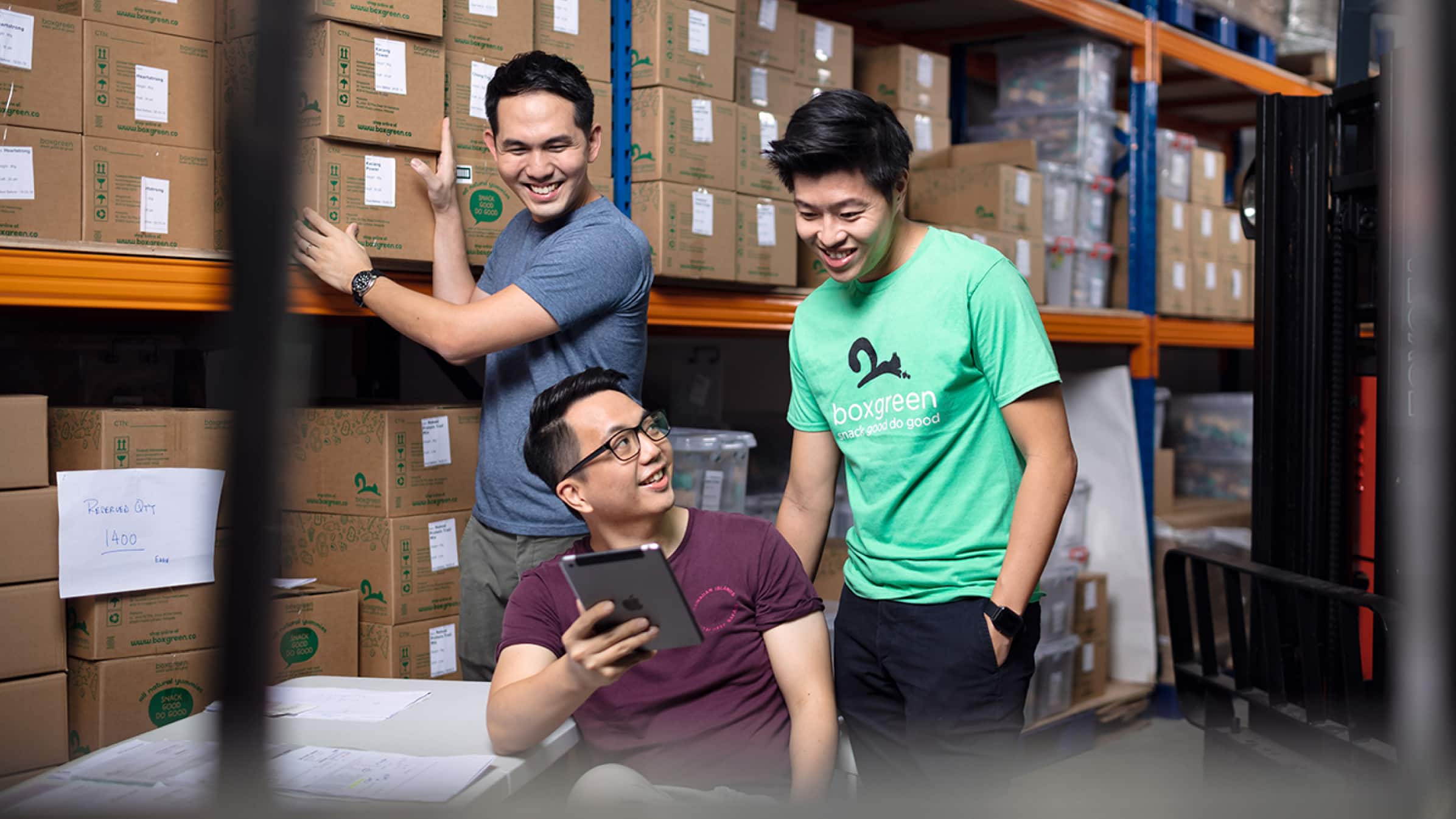 Andrew Lim and Walter Oh, founders of Boxgreen, standing in their storage warehouse with a colleague.