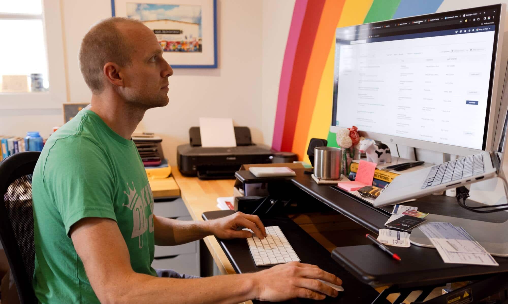 King of Pops owner Steven Carse sitting down at a desk looking at a computer screen with his hands placed on a keyboard.