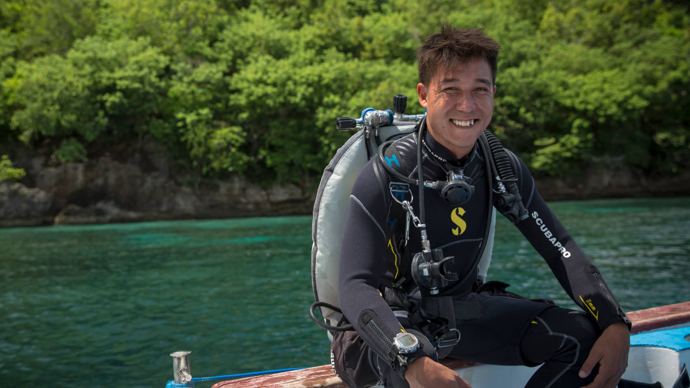 Leon Boey, owner of LivingSeas, sitting on the edge of a boat in diving gear. 