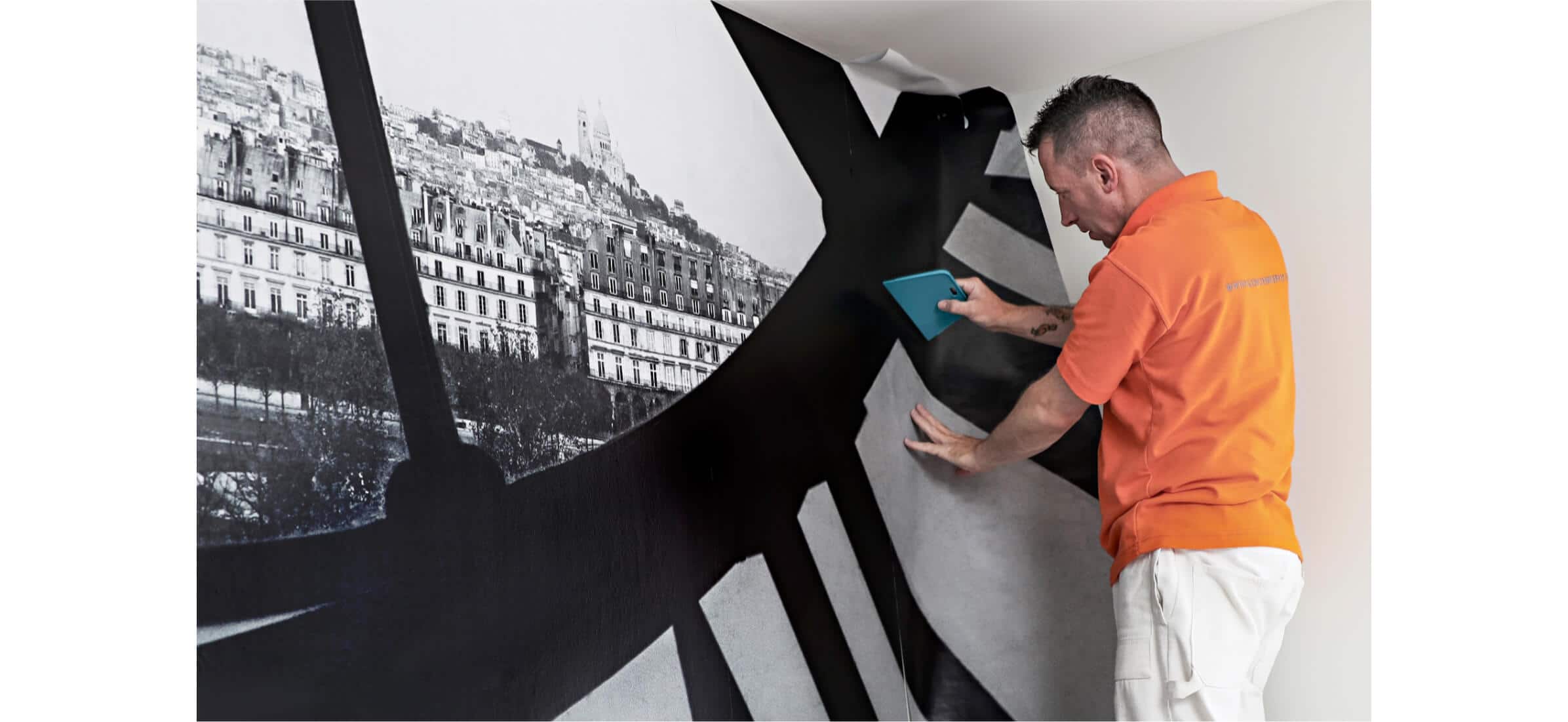 Paul Walden installing wallpaper featuring a black and white image of London.