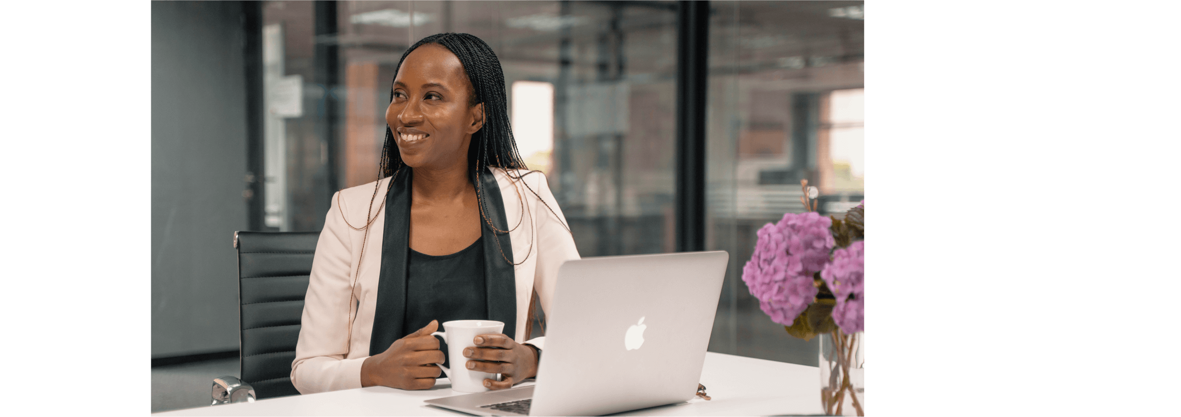 Nkhesani Kapena smiles with a cup of tea in her hands, an open laptop on the table in front of her.