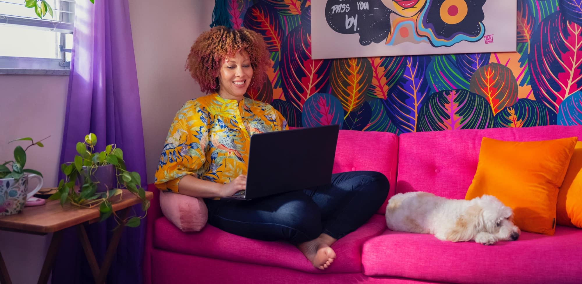 A person sits on a couch working on a laptop