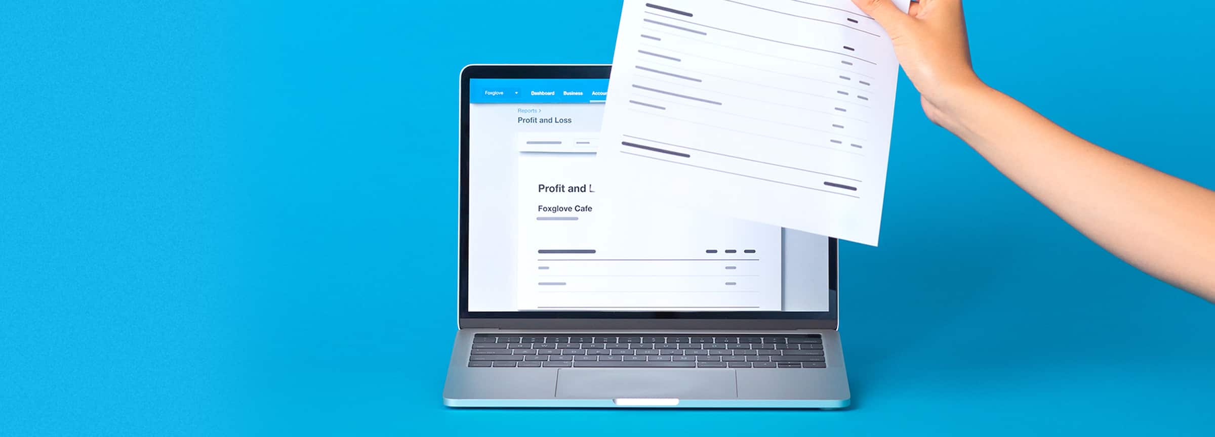 A hand holding a profit and loss statement in front of a laptop