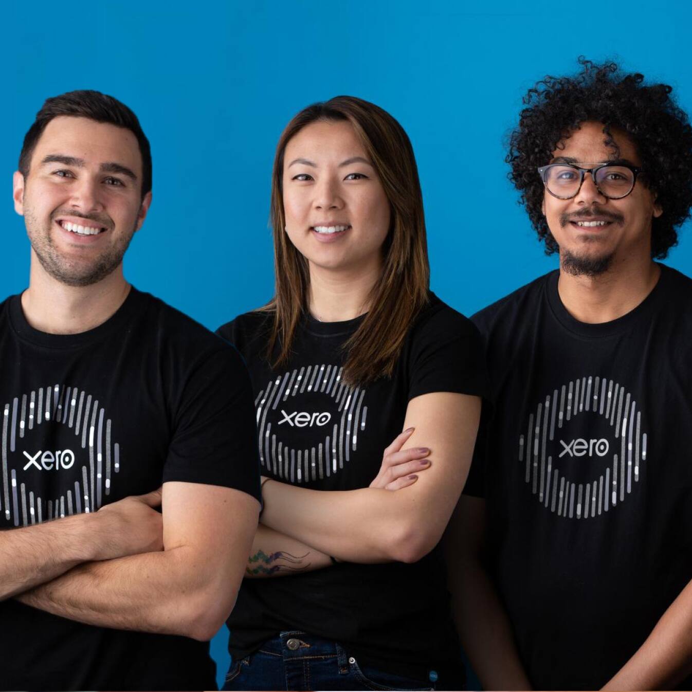 Three smiling members of the Xero team, all wearing black Xero t-shirts.